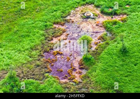 Emissione di inquinamento da acque reflue dalla città del portello sul prato con erba verde Foto Stock