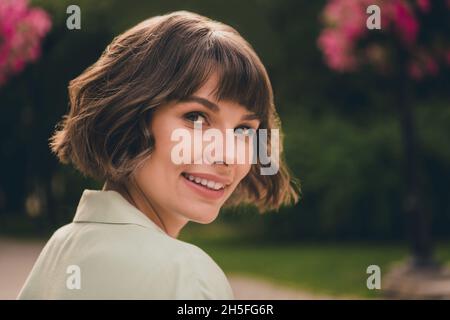 Foto di affascinante bella giovane donna indossare camicia verde sorridente camminare fuori strada della città Foto Stock