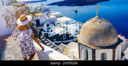 Donna in abito elegante che gode di un bellissimo paesaggio marino da Santorini Street Foto Stock