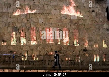 Gerusalemme, Israele. 9 Nov 2021. La gente cammina davanti alle proiezioni sulle mura della Città Vecchia vicino alla porta di Jaffa mentre la marcia Internazionale del vivere commemora Kristallnacht in tutto il mondo. La campagna globale di unità, sia luce, incoraggia la solidarietà contro l'antisemitismo, il razzismo, l'odio e l'intolleranza nella notte del 9 novembre. Kristallnacht, la Notte del vetro rotto, 9 novembre 1938, ha visto la distruzione di migliaia di sinagoghe, istituzioni ebraiche e imprese di proprietà ebraica in Germania. Credit: NIR Alon/Alamy Live News Foto Stock