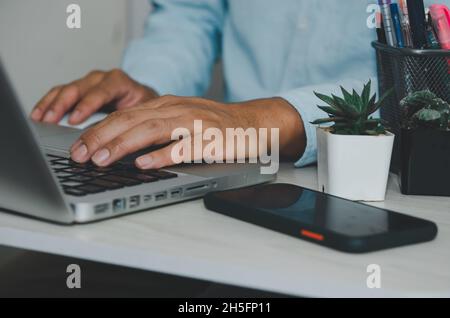 Mano dell'uomo che usa la tastiera del computer portatile. Cerca in internet, informazioni, social networks.Businesses che commerciano acquisti online. Foto Stock
