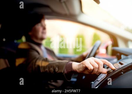 Donna che accende la radio che guida a casa in auto. Foto Stock