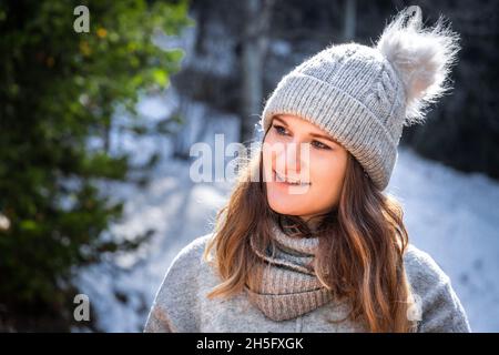 Ritratto invernale di giovane donna bionda in maglione grigio e berretto beanie all'aperto. Foto Stock