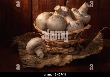 funghi in un cestino su sfondo di legno scuro in stile rustico Foto Stock