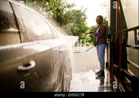Donna washes via schiuma dalla macchina, mano auto lavaggio Foto Stock