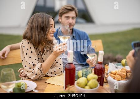 Amici bere vino al pic-nic vicino vigneti Foto Stock