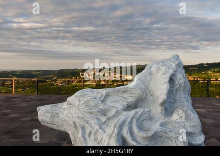 Statua raffigurante un lupo sulla terrazza panoramica di Montelupo Albese con le colline delle Langhe e la città di Rodello sullo sfondo, il Piemonte Foto Stock