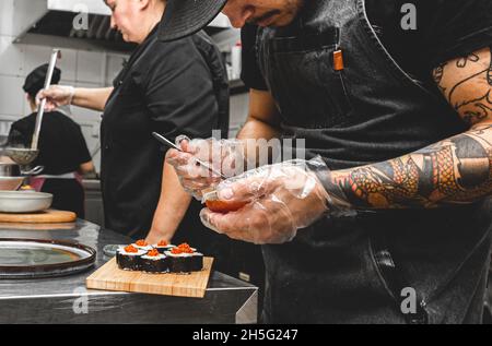 cuochi maschili che preparano il sushi nella cucina del ristorante. Foto Stock