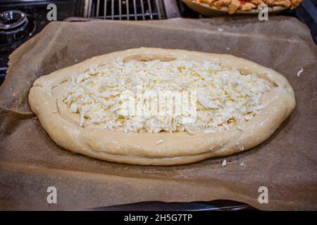 Kachapuri georgiano non cotto dell'Europa orientale - fatto con pane e formaggio - pronto per il forno - fuoco selettivo. Foto Stock