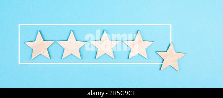 Cinque stelle su uno sfondo blu, mano mettere l'ultima stella in fila, la valutazione, dando feedback Foto Stock