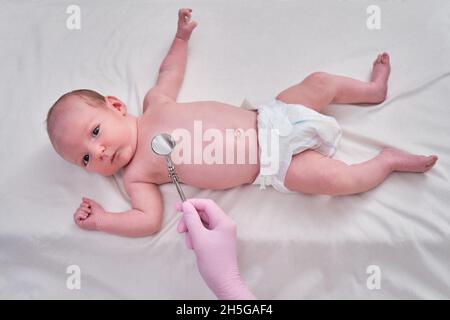 Un medico in uniforme controlla la bocca di un bambino con uno specchio. Il dentista esamina i denti di un neonato Foto Stock