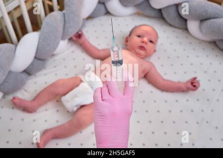 Il medico usa una siringa per iniettare un neonato. Un'infermiera in uniforme si prepara a vaccinare un bambino Foto Stock