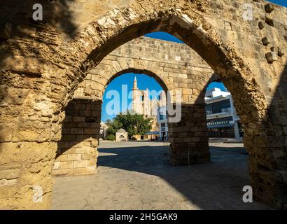 Moschea di Lala Mustafa Pasha, incorniciata attraverso gli archi del Palazzo Veneziano, Piazza Namik Kemal, Famagosta, Cipro del Nord. Foto Stock