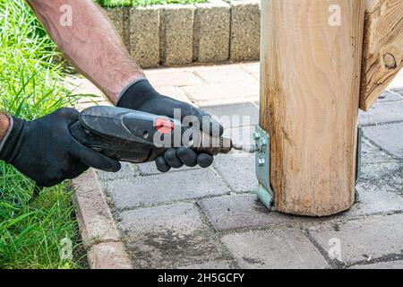 Gli operatori che indossano i guanti devono utilizzare un cacciavite elettrico per serrare la vite. Foto Stock