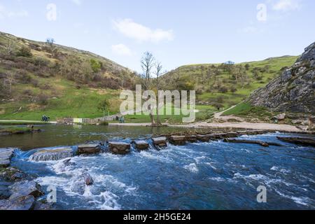 I turisti hanno visto esplorare Dovedale intorno alle pietre bagnate del passo nel novembre 2021 dopo le piogge pesanti parzialmente inondato la valle. Foto Stock