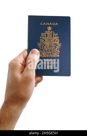 Primo piano su una mano dell'uomo che tiene un passaporto canadese su uno sfondo bianco. Foto Stock