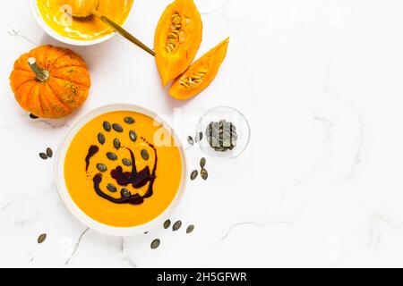 Zuppa di zucca fatta in casa con olio di zucca e semi su sfondo di marmo Foto Stock