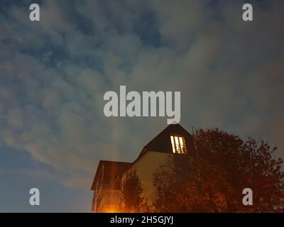 Luce che splende attraverso una finestra di notte Foto Stock