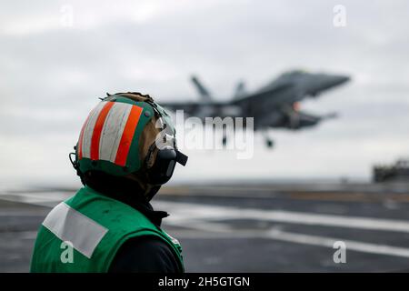 OCEANO PACIFICO (Nov. 6, 2021) Aviation Boatswain's Mate (Equipment) 1st Class Nabil Pareja, da Richmond, California, osserva un EA-18G Growler, assegnato ai 'Wizards' di Electronic Attack Squadron (VAQ) 133, fa un atterraggio arrestato sul ponte di volo della portaerei USS Abraham Lincoln (CVN 72). Abraham Lincoln sta conducendo le operazioni di routine nella terza flotta degli Stati Uniti. (STATI UNITI Foto Navy di Mass Communication Specialist terza classe Michael Singley/rilasciato) Foto Stock