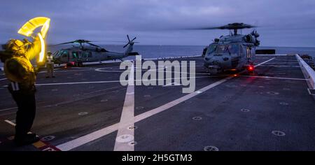 OCEANO PACIFICO (Nov. 6, 2021) Airman Kevon Lamont-Anderson di Aviation Boatswain, di Cleburn, Texas, assegnato alla nave portuale di trasporto anfibio USS John P. Murtha (LPD 26), Dirige un elicottero MH-60S Seahawk attaccato alle "Wild Cards" di Helicopter Sea Combat Squadron (HSC) 23 per salire dal ponte di volo durante il NASA in corso Test di recupero nove (URT-9), 6 novembre. Questo segna il nono test di recupero in corso della Marina degli Stati Uniti a sostegno della missione della NASA Artemis e la terza volta che un URT ha avuto luogo a bordo di John P. Murtha. La Marina degli Stati Uniti ha molte capacità uniche che la rendono un partner ideale f Foto Stock