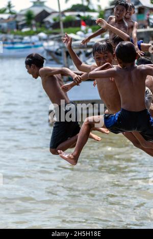 I bambini saltano fuori dal traghetto che attraversa il molo di sumbawa, Indonesia Foto Stock