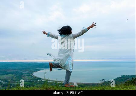 Happy girl jumping con una vista di geo parco ciletuh, ovest java, Indonesia Foto Stock