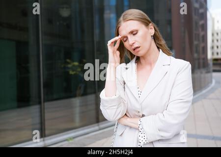 Dipendente femminile frustrato in ufficio sensazione di ansia per il problema del lavoro, frustrata mediocre donna d'affari di mezza età che soffre di problemi di salute, lottando con il mal di testa Foto Stock