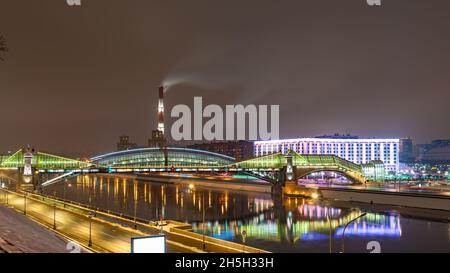 Vista del colorato ponte Bogdan Khmelnitsky illuminato di notte che si riflette nel fiume Moskova. Ponte pedonale sul fiume Moskva. Mosca Foto Stock