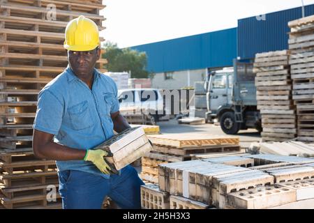 Uomo che trasporta blocchi cavi di calcestruzzo all'aperto Foto Stock