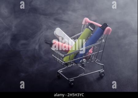 Vapes usa e getta in un carrello su sfondo nero. Sigarette elettroniche moderne. Foto Stock