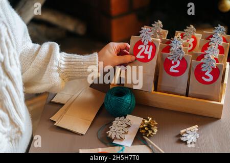 Primo piano vista dall'alto della giovane donna irriconoscibile attacca il numero sulla borsa del mestiere, si fissa con clothespin e mette via in vassoio di legno Foto Stock