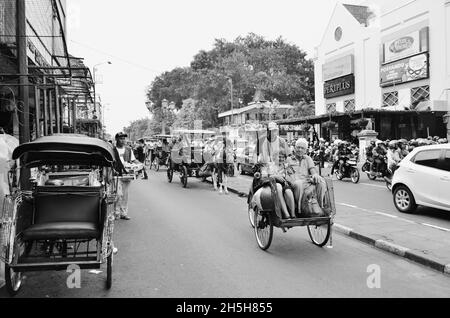 Passeggero e autista in risciò tradizionale, Jalan Malioboro, Yogyakarta, Indonesia Foto Stock