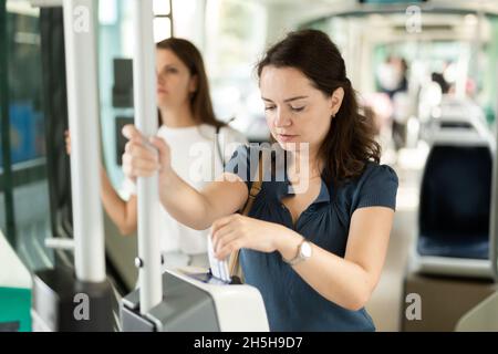 Donna che convalida il biglietto nei trasporti pubblici Foto Stock