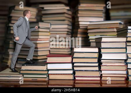 un uomo in tuta sale le scale dei libri Foto Stock