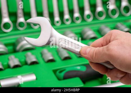 Un set di attrezzi per la riparazione in assistenza auto - mani del meccanico, primo piano. Meccanico automatico con strumenti di lavoro per la riparazione e la diagnostica di automobili nella gara Foto Stock