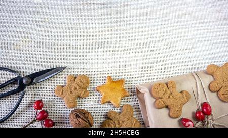 Biscotti domestici dell'uomo dello zenzero, decorazione per Natale, forbici, su uno sfondo rustico del panno. Primo piano. Foto Stock