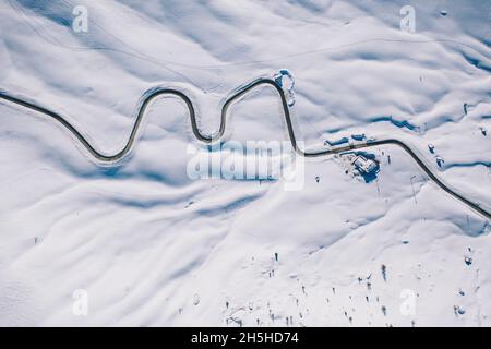 Tornanti di strada di montagna innevata dall'alto, vista aerea, Dolomiti, Italia Foto Stock