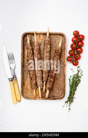 Kebab di montone di agnello sminuzzato e modellato, su sfondo di tavola di pietra bianca, con vista dall'alto e piatto Foto Stock