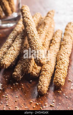 Grissini di grissini. Bastoncini di pane con semi di sesamo su tavola di legno. Foto Stock