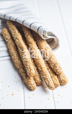 Grissini di grissini. Bastoncini di pane con semi di sesamo su tavola di legno. Foto Stock