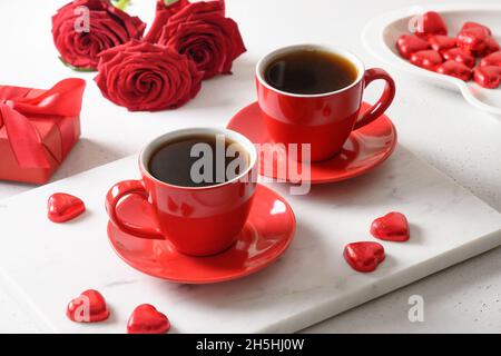 San Valentino datazione con caffè, dolci al cioccolato rosso e rose su bianco. Primo piano. Appuntamento romantico per due. Foto Stock