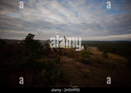 Castello di Ogrodzieniec visto da lontano, paesaggio mozzafiato con rovine del castello in lontananza, foresta, rocce e colline Sentiero dei nidi delle aquile, Polonia Foto Stock