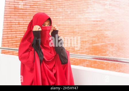 Donna in abito rosso niqab Foto Stock