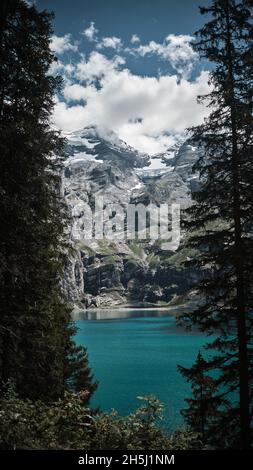 Lago di Oeschinen circondato da vette innevate in Svizzera Foto Stock