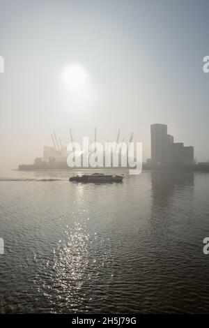 Misty mattina presto Tamigi fiume, Uber Boat Tamigi Clippers fiume traghetto e O2 Arena luogo di intrattenimento, Greenwich Peninsula, East London, United Foto Stock