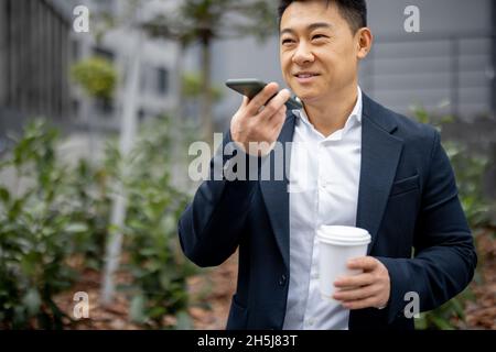 Uomo d'affari con una tazza di caffè che chiama sullo smartphone Foto Stock
