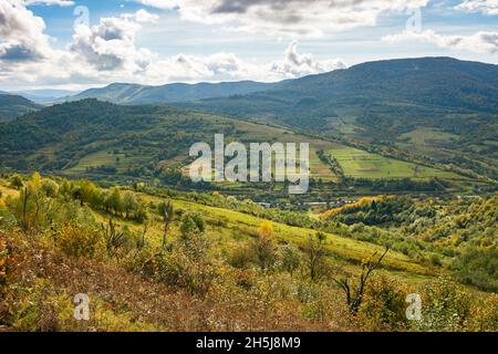 paesaggio di campagna carpaziana all'inizio dell'autunno. bellissimo paesaggio di montagna con luce appollata. caldo giorno di sole con nuvole sul cielo Foto Stock