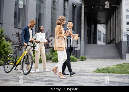 Il team aziendale in maschere mediche a piedi e parlare Foto Stock