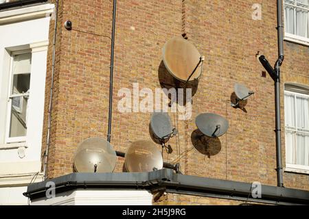 Una gamma di piatti satellite di dimensioni diverse in un edificio residenziale di Londra. Foto Stock