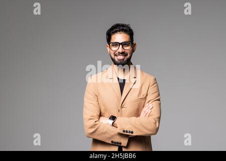 Ritratto di una smart giovane uomo in piedi con le braccia incrociate contro uno sfondo grigio Foto Stock